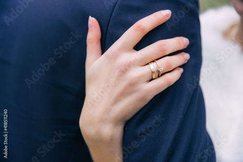 the bride's hand in wedding rings hugs the groom's shoulders.wedding concept.