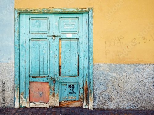 A very old coffered wooden door painted with turquoise paint © AkimaFutura