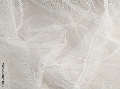 White mosquito net fabric texture with folds. Wavy chiffon background. Full frame of crumpled white cloth material texture. Abstract white net fabric pattern for patterns and designs.