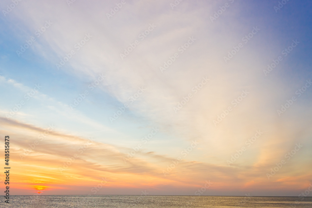 Sunset sky over sea in the evening on sundown with orange sunlight clouds background 