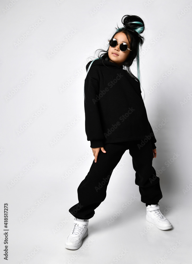 Young girl wearing blank and oversize long hoody. Concrete wall background. Vertical Young girl wearing blank and oversize long hoody. Concrete wall background. Vertical