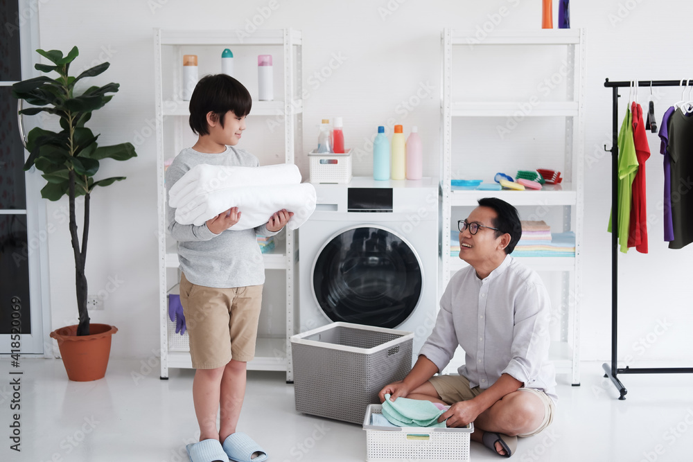 Smiling Asian father and little boy child is hugging for enjoying and Washing together in Laundry room on holiday. Family activities and child educational for homeschool concept. Smiling Asian father and little boy child is hugging for enjoying and Washing together in Laundry room on holiday. Family activities and child educational for homeschool concept.