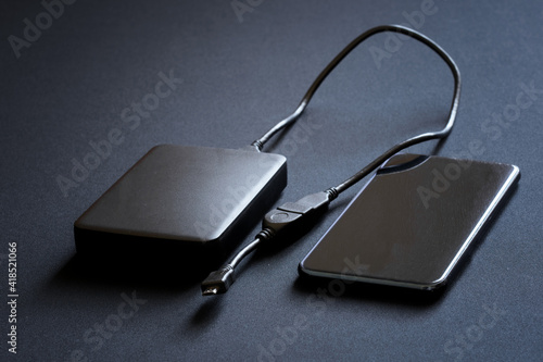A smartphone and an external hard drive with an OTG cable and an adapter for connecting to gadgets lie on a gray background