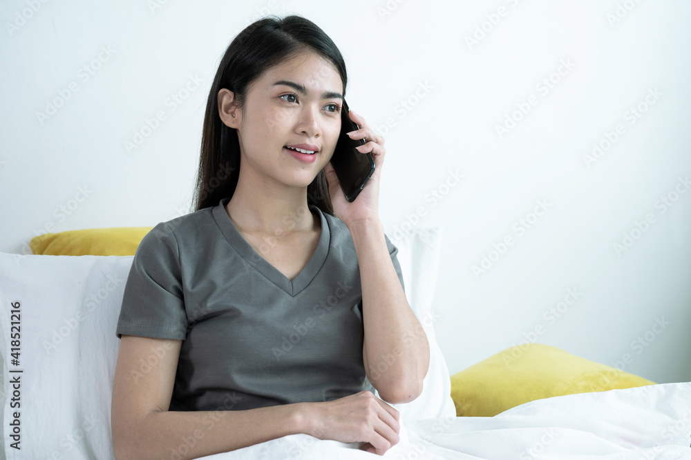 Young beautiful Asian woman sitting on a cell phone talking on the sofa at home. Young beautiful Asian woman sitting on a cell phone talking on the sofa at home.