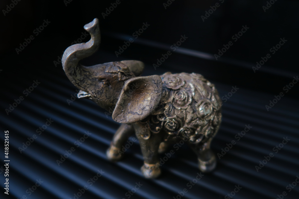 Fototapeta premium Golden elephant figurine on black background