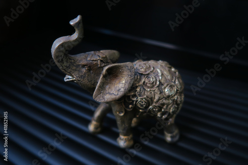 Golden elephant figurine on black background
