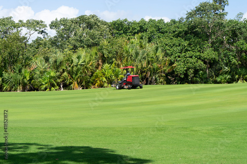 Gower grass equipment working on a summer day. Lawn mowing, Mexico. Gardener cuts green grass on the perfect golf course.