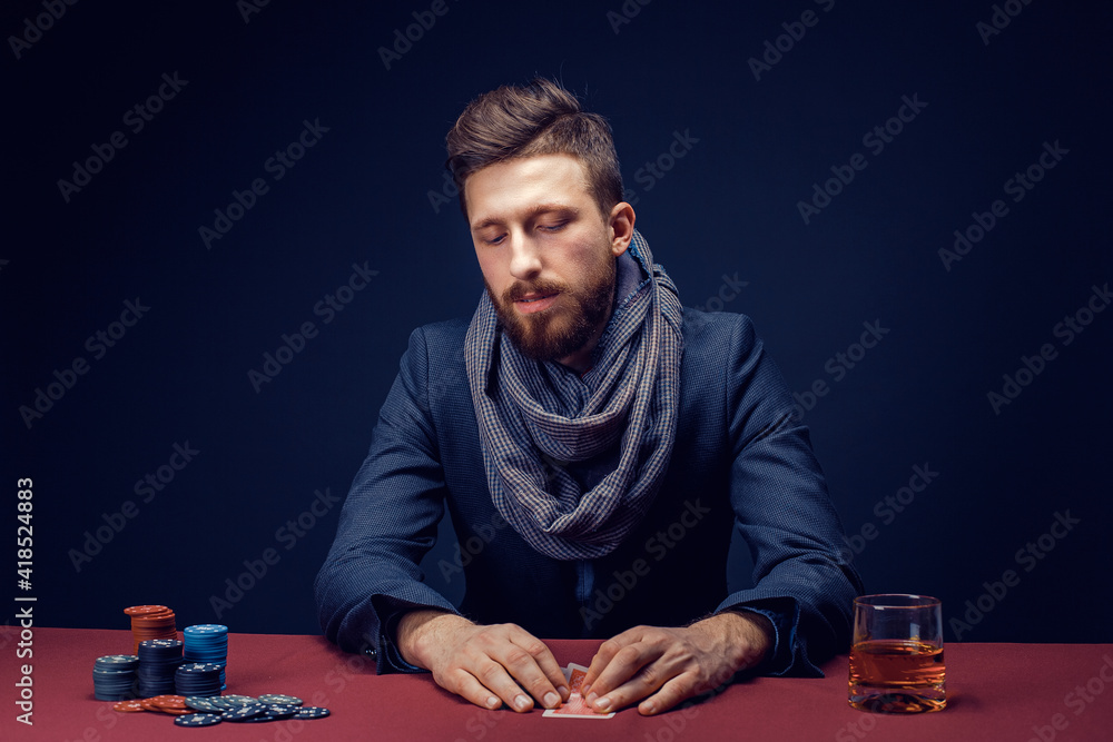 Stylish bearded Man in suit and scarf playing in dark casino, smoking cigar, drink whiskey. Stylish bearded Man in suit and scarf playing in dark casino, smoking cigar, drink whiskey.
