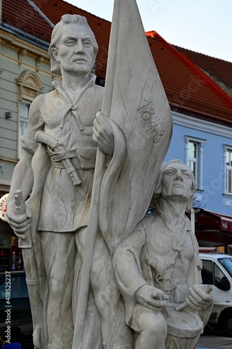 Statue of two Slovak volunteer soldiers from Slovak Uprising of 1848/1849, first holding flag and rifle, with percussion pistol behind his belt. Buildings on Sturova street in background.  photo