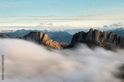 Mountains in fog at beautiful sunset in autumn in Big Thach Natural Park, Russia. Landscape with alpine mountain valley, low clouds, forest, blue sky. Aerial view
