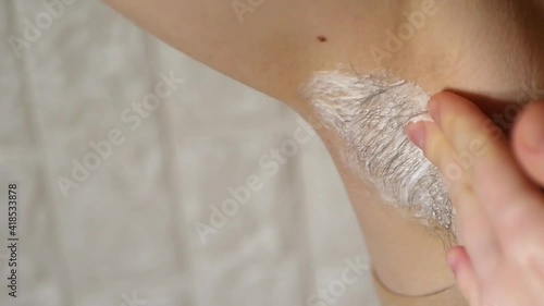 Close up armpit hair removal. Shaving underarm with razor. Applying cream. 