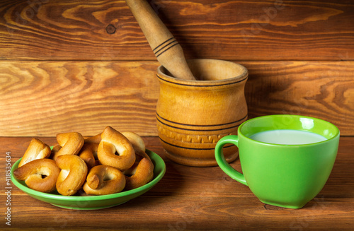 Milk mug and green plate with homemade bagels on vintage boards. Idea for a delicious festive breakfast or dinner