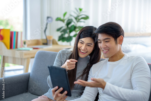 Go smiling Asian woman and play tablet on the sofa in the living room..
