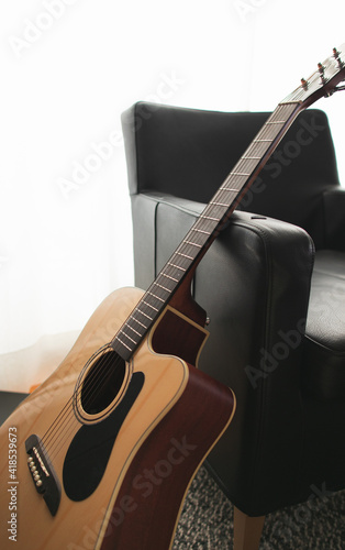 An acoustic guitar propped up on a chair in the living room