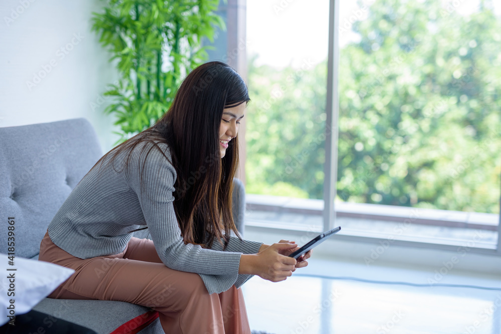 A woman using a tablet computer Smiling, looks cheerful and bright.. A woman using a tablet computer Smiling, looks cheerful and bright..