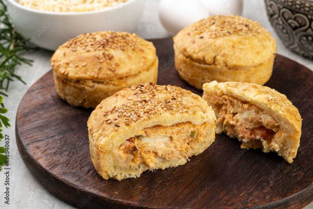 Homemade chicken pies over wooden board with ingredients Homemade chicken pies over wooden board with ingredients