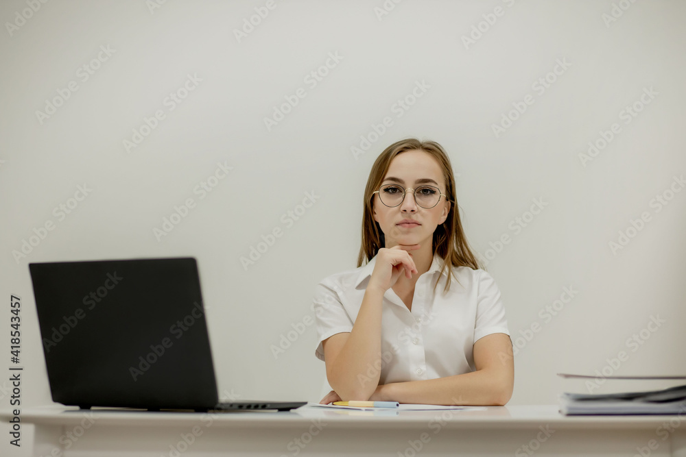 Close-up portrait of a young confident female office manager at her workplace, ready for doing business task. Close-up portrait of a young confident female office manager at her workplace, ready for doing business task.