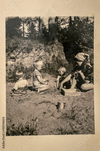 Germany - CIRCA 1930s: Group photo of mother and tree small kids sitting in garden. Vintage archive Art Deco era photography