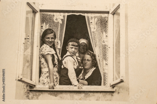 Latvia - CIRCA 1930s: A family sitting together in a window sill group shot. Children lived in a three generation family household. Vintage art deco era photo photo