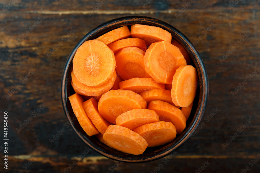 Sliced carrots in a bowl on a wooden background. Vegetable, ingredient and staple food. Sliced carrots in a bowl on a wooden background. Vegetable, ingredient and staple food.