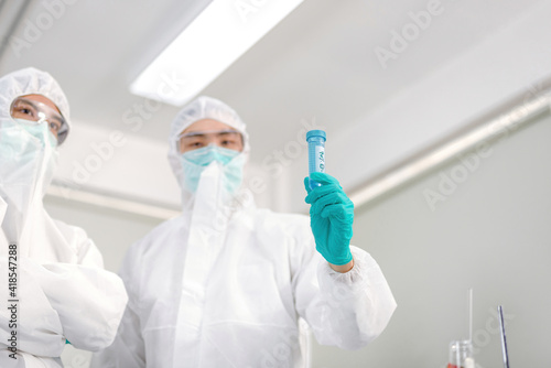 A man in a ppe suit holding a virus science.