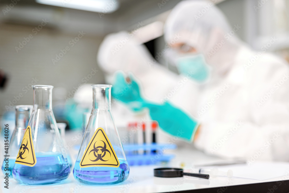 A bottle with a sign Dangerous chemicals and Number background scientist wear ppe suit. A bottle with a sign Dangerous chemicals and Number background scientist wear ppe suit.