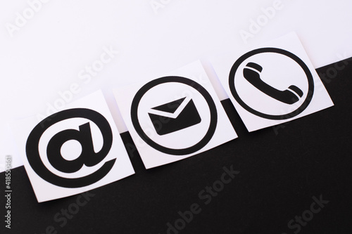 Online business communication symbols of telephone, email and mail address on a black and white background. Contact us or e-mail marketing concept