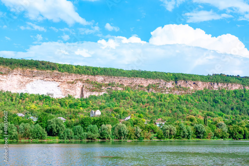 River shore and green hill . Coastal settlement in the summer