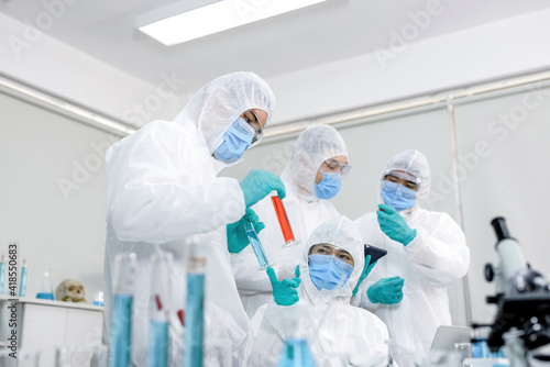 A lab of 4 scientists pretending to be happy inside a ppe suit with protective equipment  a doctor mask and a white ppe suit..
