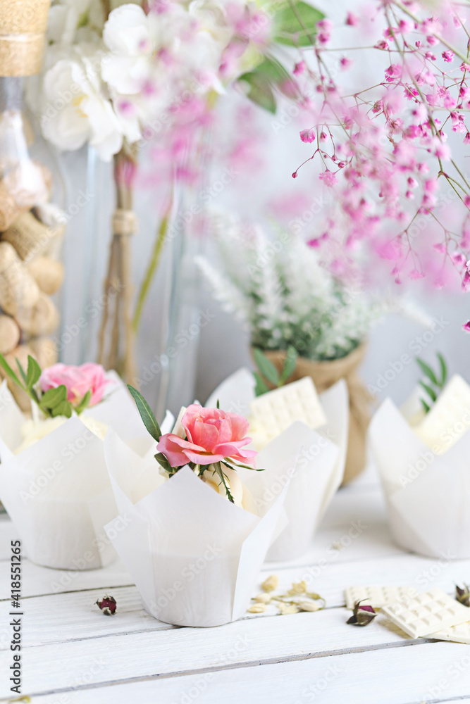 Several cupcakes and muffins with white butter cream and a lively pink rose on a white wooden table. Valentine's day or Mother's Day gift. Fresh flowers are on the table nearby. Rustic style. Several cupcakes and muffins with white butter cream and a lively pink rose on a white wooden table. Valentine's day or Mother's Day gift. Fresh flowers are on the table nearby. Rustic style.