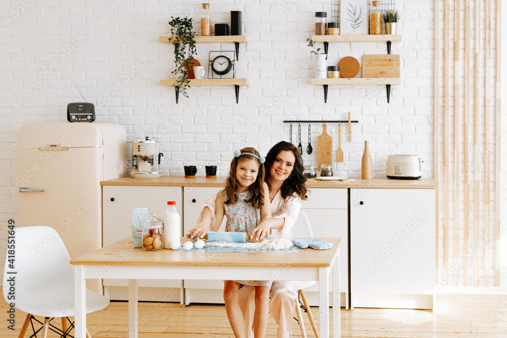 A happy family spends time together baking food in the kitchen. Mom teaches her daughter to cook and knead dough. Mother's Day concept.
A happy family spends time together baking food in the kitchen. Mom teaches her daughter to cook and knead dough. Mother's Day concept.