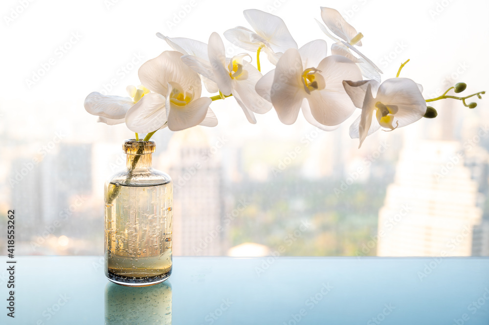 Fototapeta premium The glass table with white flowers in the vase and cityscape in the background