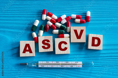 ASCVD - acronym on wooden cubes on a blue background with tablets and thermometer photo