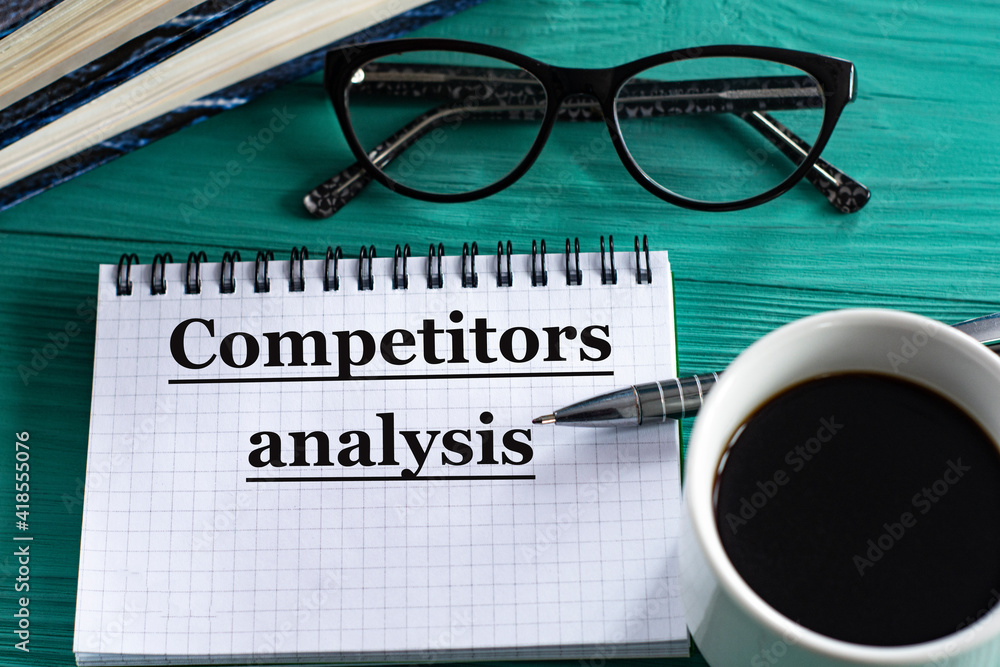 COMPETITORS ANALYSIS - words in a notepad on a wooden green background with a calculator, pen and glasses COMPETITORS ANALYSIS - words in a notepad on a wooden green background with a calculator, pen and glasses