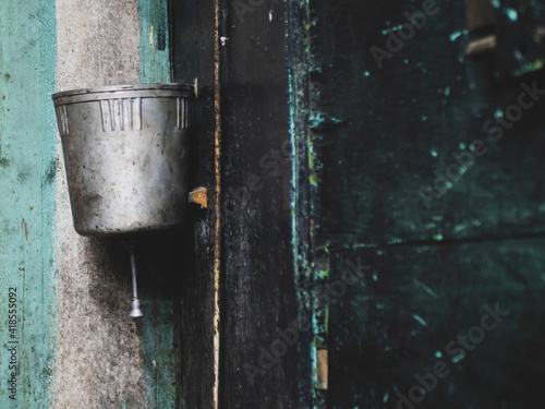 Fotografi Old metal washstand is hanging on the peeling black wall