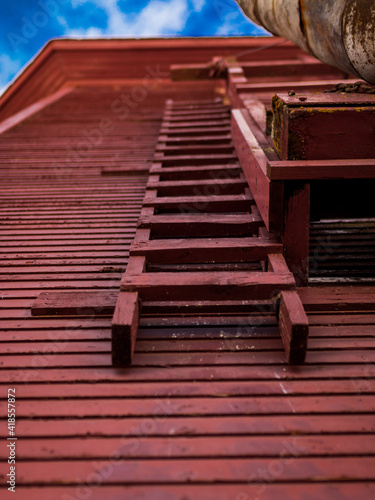 A historic red water tower used for the railroad.  POV looking up the tower ladder