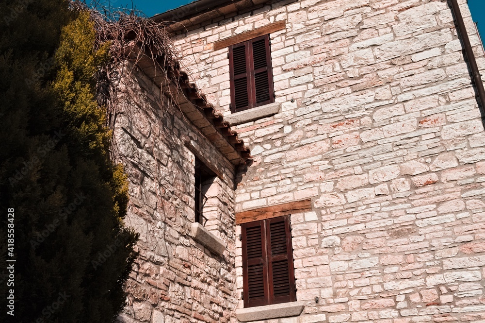 A window with wooden shutters of a medieval brick building (Marche, Italy, Europe) A window with wooden shutters of a medieval brick building (Marche, Italy, Europe)