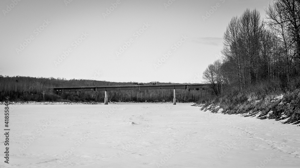 Views of concrete and steel bridge crossing a frozen North Saskatchewan River, Hensberg Alberta Canada.  Hiking the Iron Horse trail in the winter