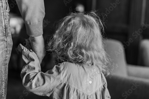 Father leads his child daughter by the hand. Indoors, black and white background. Trust,family concept. Selective focus