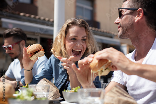 happy lovers eating big burgers outdoors