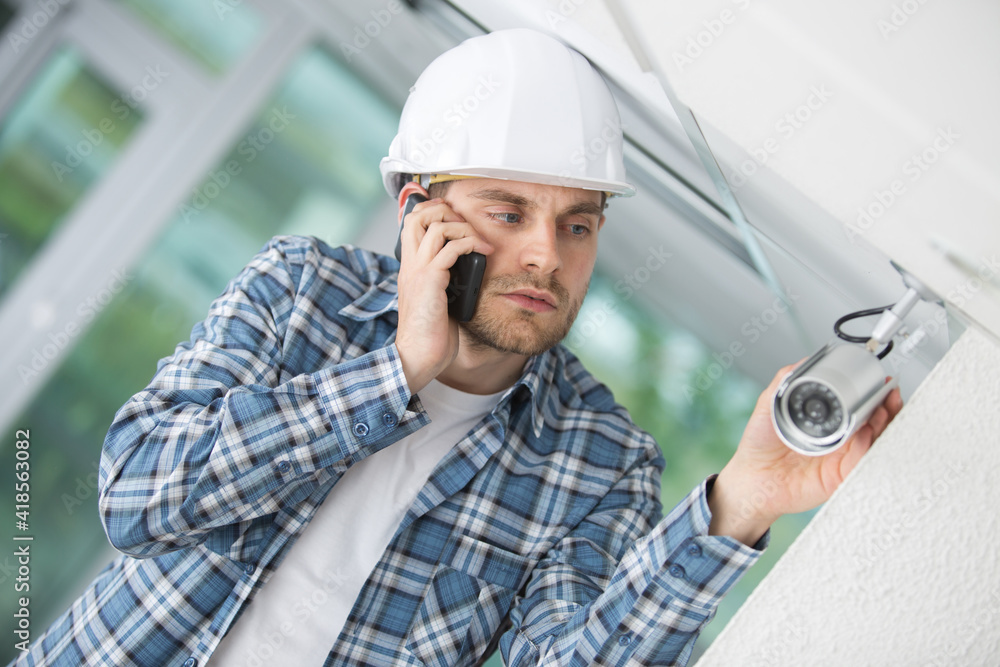 contractor checking security camera and talking on telephone contractor checking security camera and talking on telephone