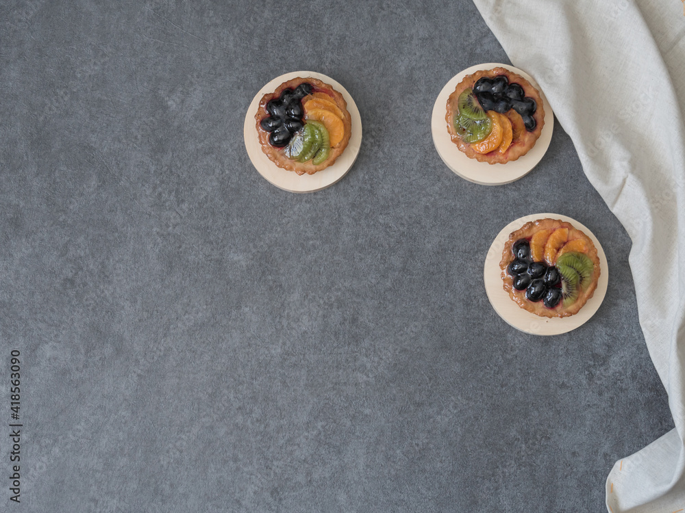 Tartlets with fruits on a gray background. View from above. Tartlets with fruits on a gray background. View from above.