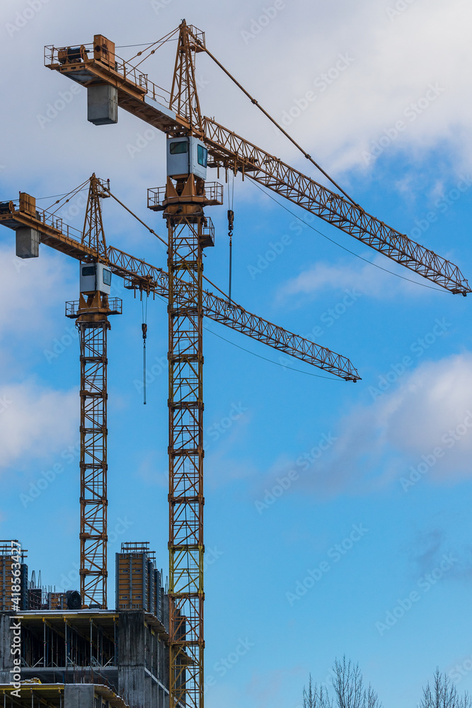 Construction site with high-rise cranes. Construction of modern apartment buildings and a new residential complex. Blue sky.