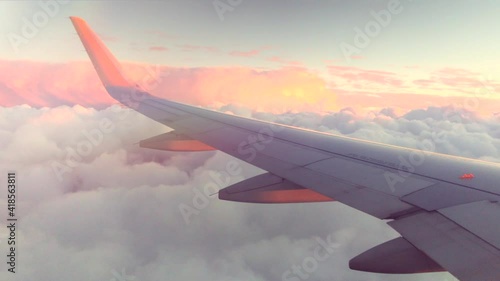 Airplane flight. Wing of an airplane flying above the clouds with sunset sky. View from the window of the plane. Airplane, Aircraft. Traveling by air. 4K UHD video 