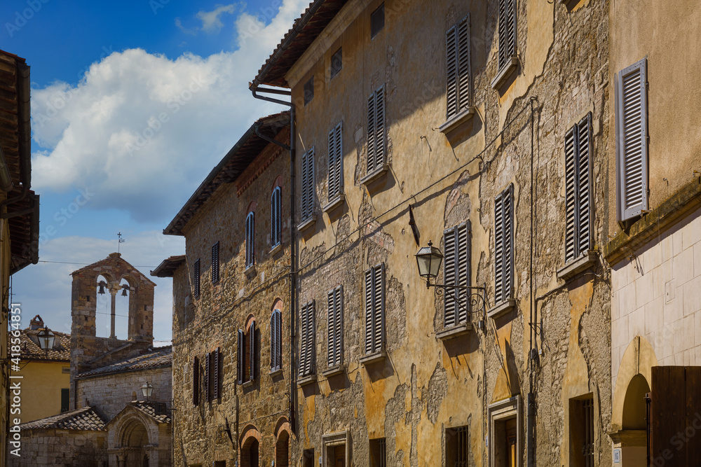 Medieval buildings along the main street with the church of Santa Maria Assunta, San Quirico d'Orcia, Italy