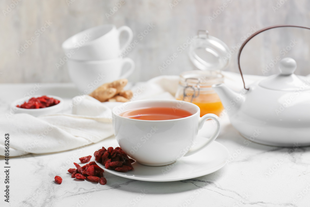 Cup with goji tea on light background