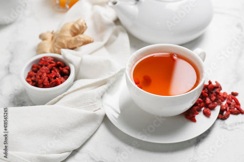 Cup with goji tea on light background