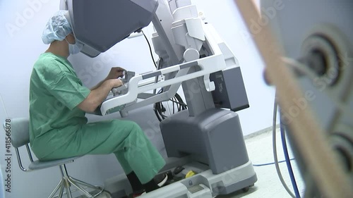 Doctor operates with a medical robot looking inside the monitor.