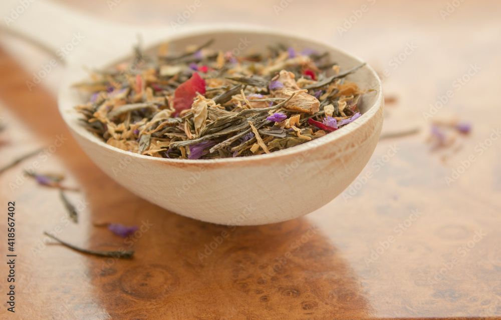 Fototapeta premium Tea in a wooden spoon on a wooden background close up