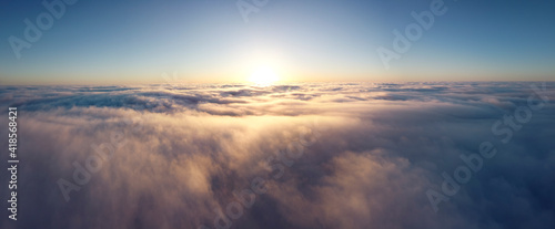 Sunrise over the clouds high in the sky. Panorama of the sun over the morning mist.